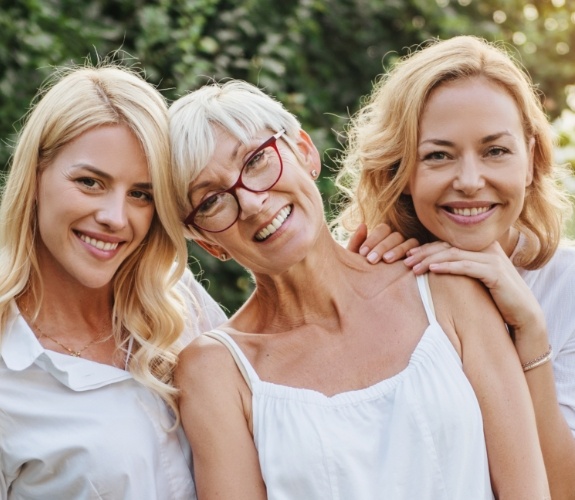 Three generations of woman smiling after dental implant tooth replacement