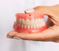 Hands holding dental implant supported full dentures