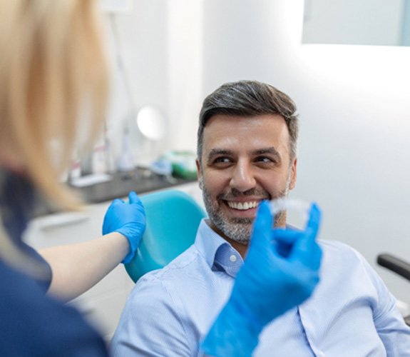 A dentist showing an Invisalign aligner to her patient