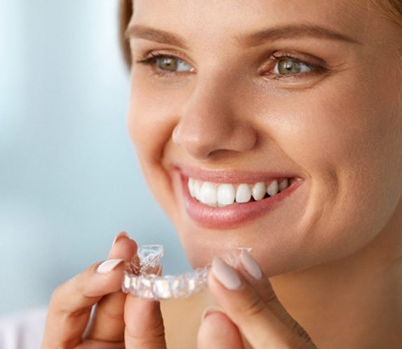 A woman holding an over-the-counter whitening tray 