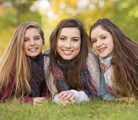 Two teens with traditional braces and one with clear braces
