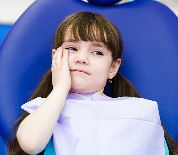 Child in need of pulp therapy holding cheek