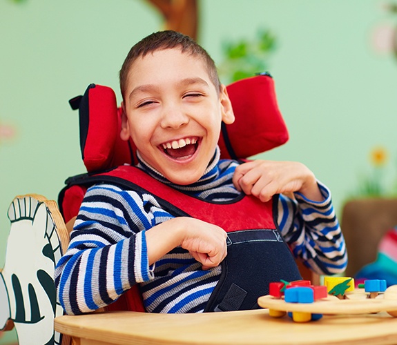 Child laughing in classroom after special needs children's dentistry