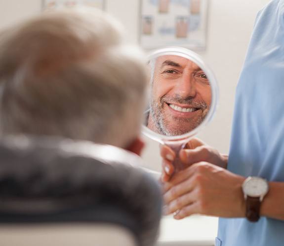 Man looking in mirror after smile makeover