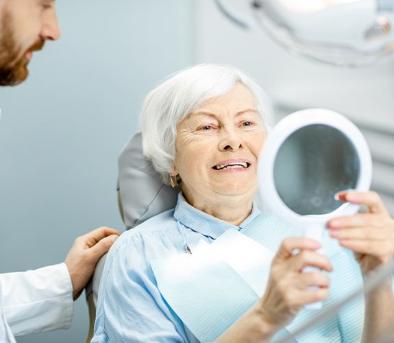 Woman with dental crown supported fixed bridge restoration looking at her smile