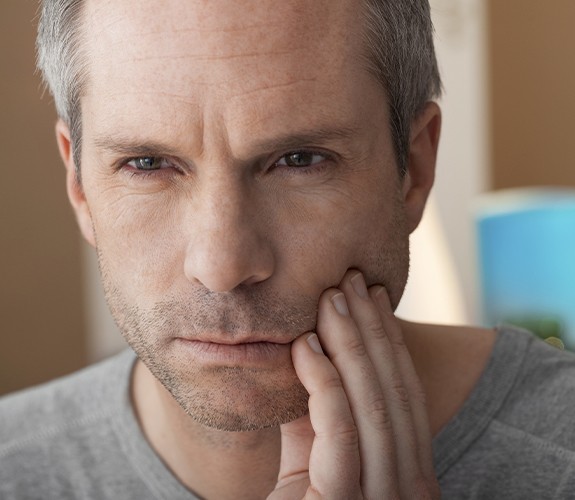 Man in need of emergency dentistry holding his jaw