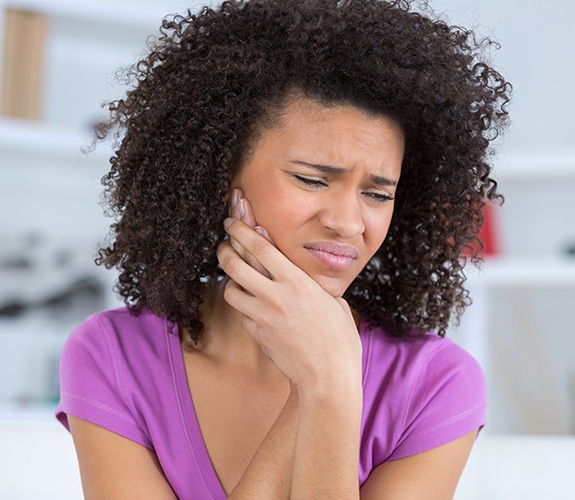 Woman in need of emergency dentistry holding jaw