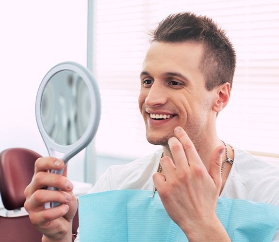 Man looking at flawless smile after dental implant tooth replacement