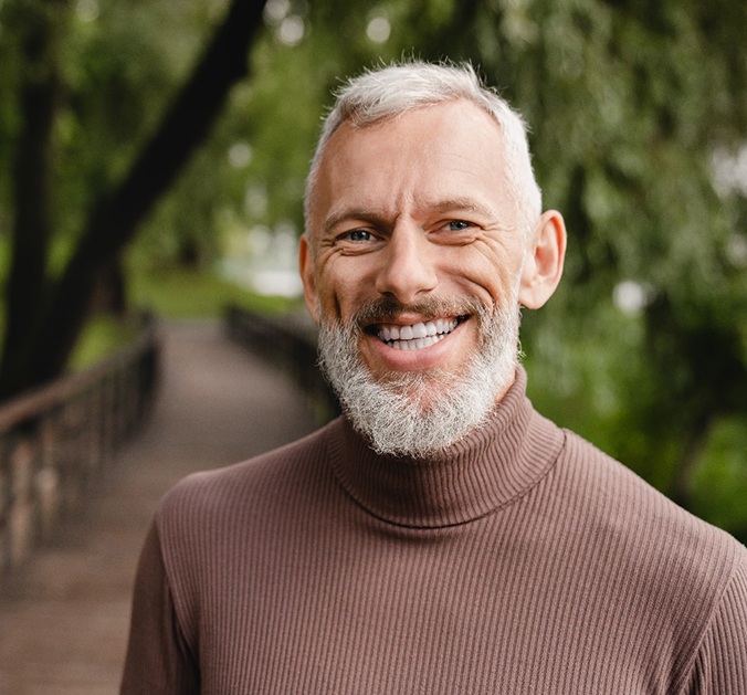 Man on a bridge with implant dentures in Marion, IN