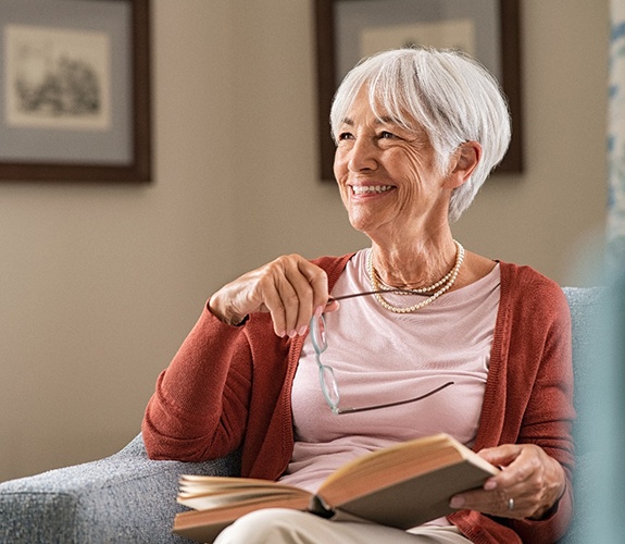 Senior woman with implant dentures in Marion, IN holding glasses