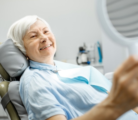 Woman looking at her smile after dental implant tooth replacement