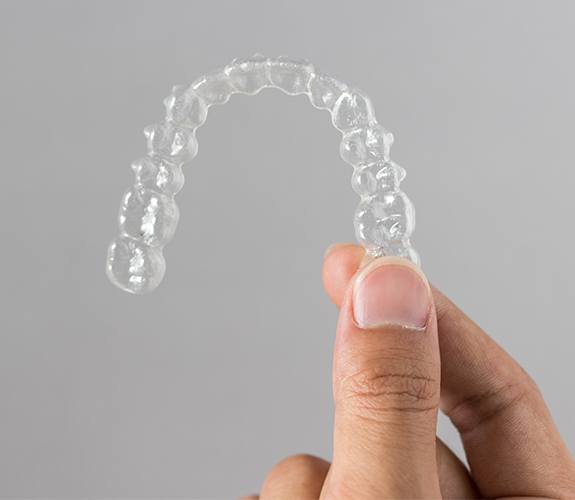 Hand holding Invisalign tray