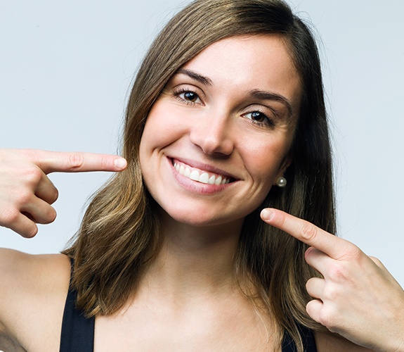 Woman pointing to smile after orthodontic treatment