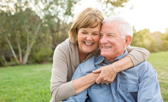 Man and woman smiling after replacing missing teeth