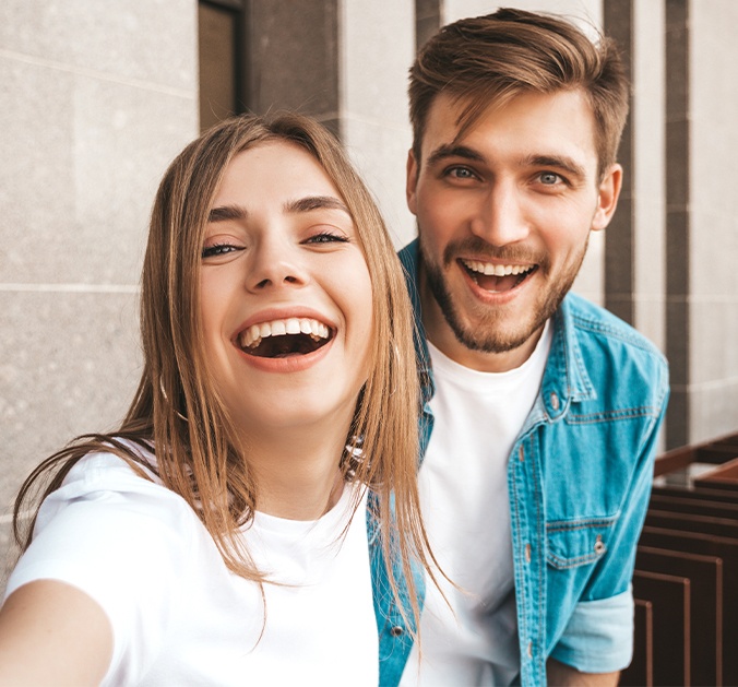 Man and woman showing off beautiful new smiles after porcelain veneers