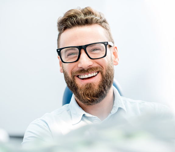 man smiling while sitting in treatment chair 