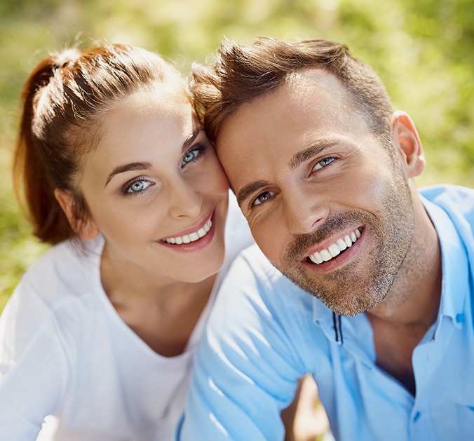 Man and woman with bright smiles after teeth whitening treatment