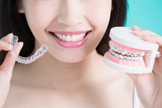 Woman holding clear tray and braces in different hands