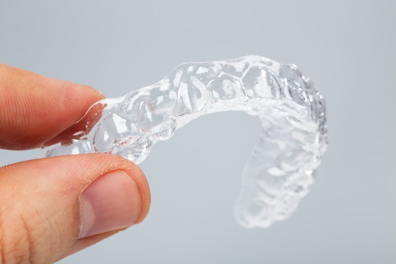 A person holding a clear aligner from Invisalign in Marion.