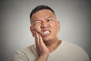 Pained man with hand on cheek has dental emergency