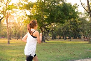 Woman with tooth pain running in park.