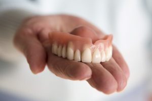  Hand holding upper denture